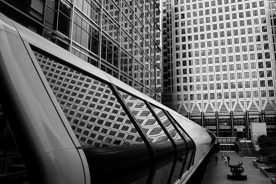 persons standing infront of building, people walking on hallway near buildings greyscale photography HD wallpaper