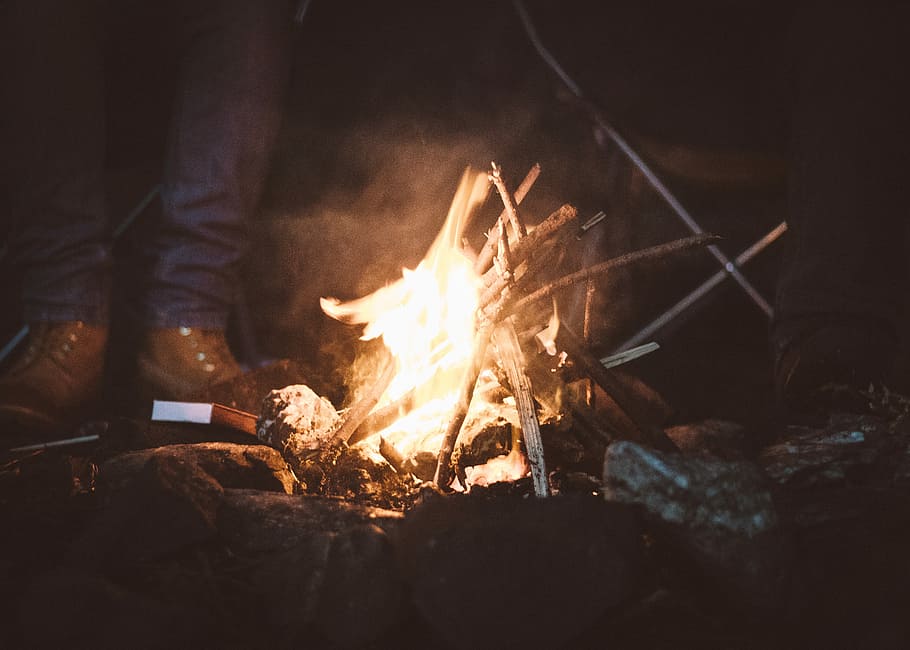 person standing near campfire, person beside bonfire during nighttime HD wallpaper
