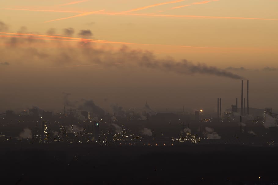 silhouette of buildings and factories during sunset, pollution