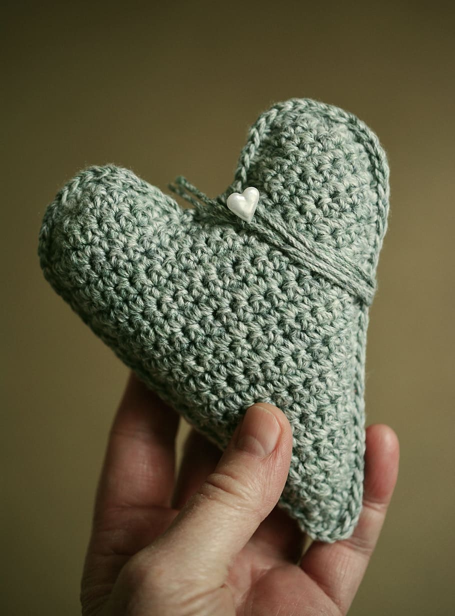 person holding gray heart knit decor, hand labor, crochet, wool