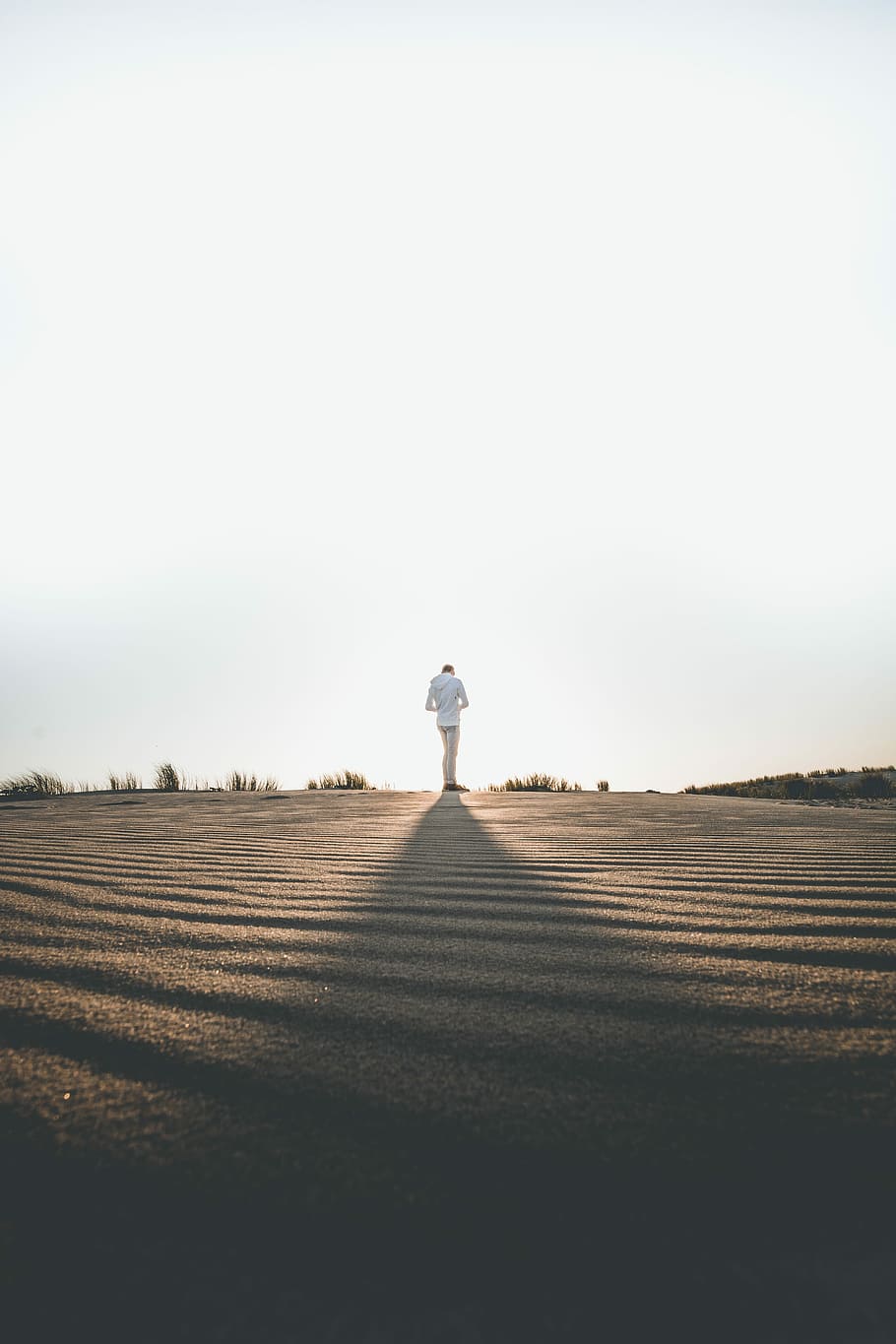 person wearing white dress shirt standing on gray surface, person standing on the open ground