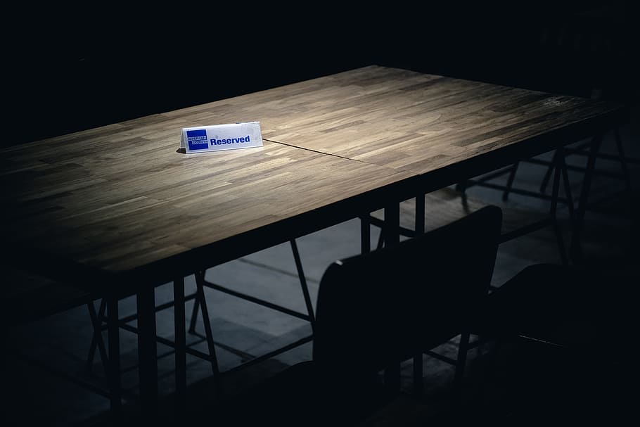 white and blue reserved signage on brown table, brown wooden table with reserved signage