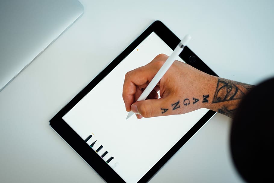 person holding white stylus writing on black iPad, person writing on iPad using white stylus