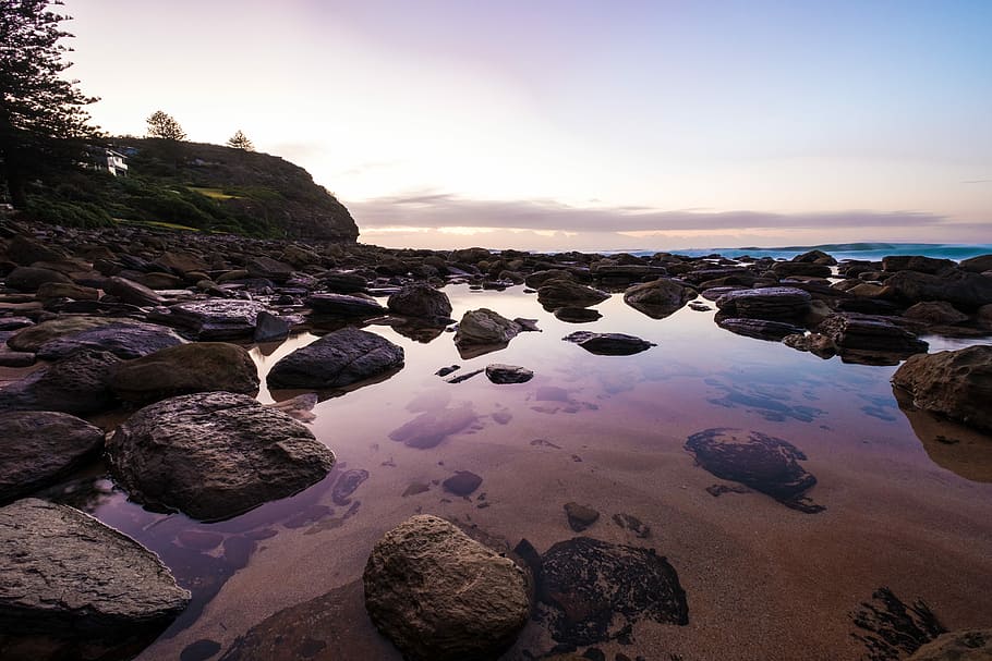 aerial view photography of rocks on shore, reflective photography of stones and sky HD wallpaper
