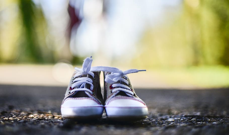 pair of grey sneakers on concrete floor, baby shoes, outdoor