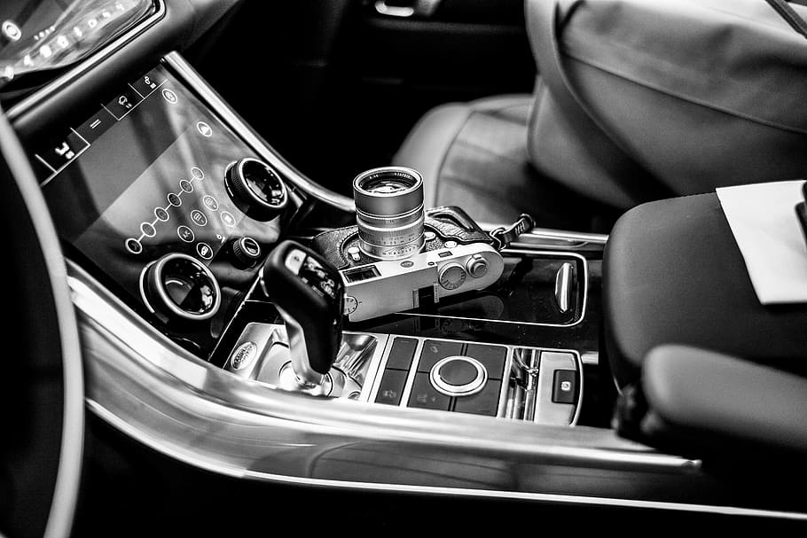 grayscale photo of SLR camera on vehicle center console, grayscale photography of point-and-shoot camera on vehicle center stack HD wallpaper