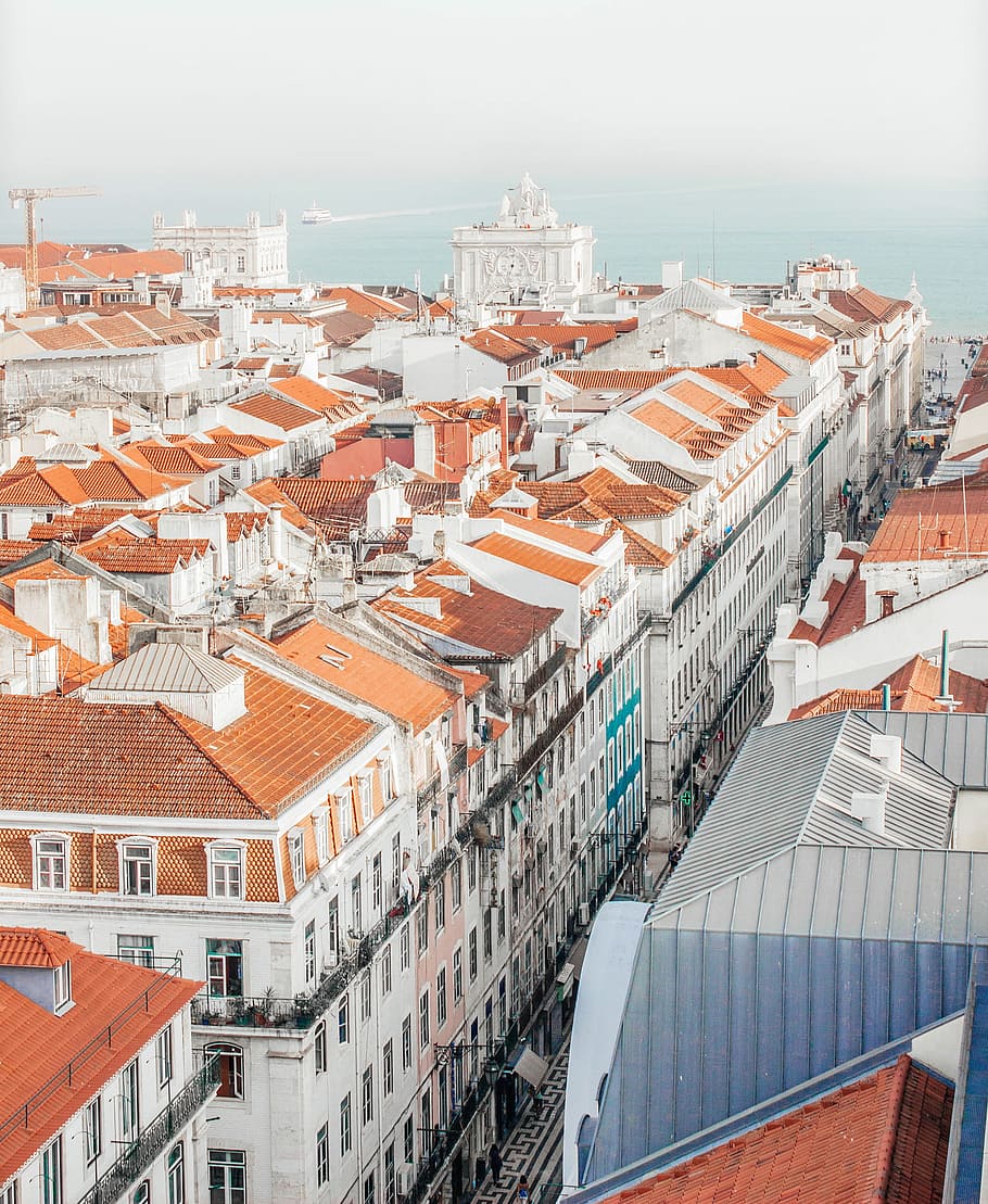 aerial photography of white houses with orange roofs during daytime, aerial view of concrete houses beside sea under white sky during daytime HD wallpaper