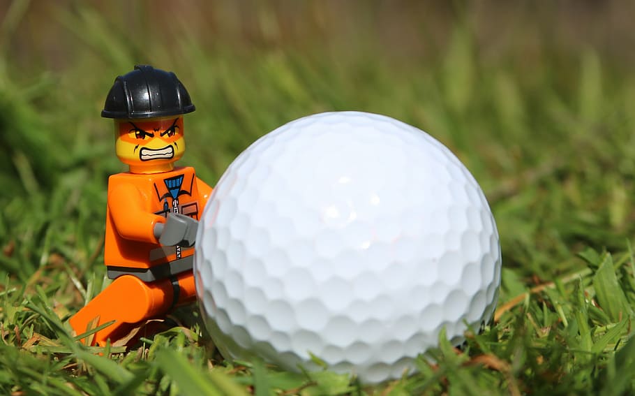 orange LEGO character minifig near golf ball, angry, funny, toy man