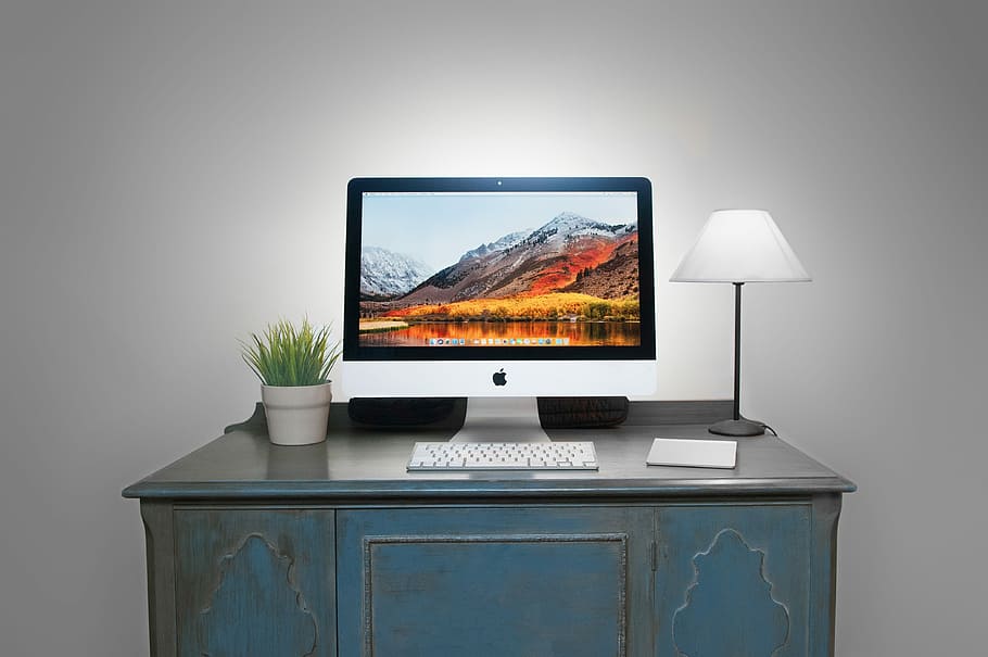 silver iMac and Apple Magic Keyboard on table, white iMac with keyboard on desk