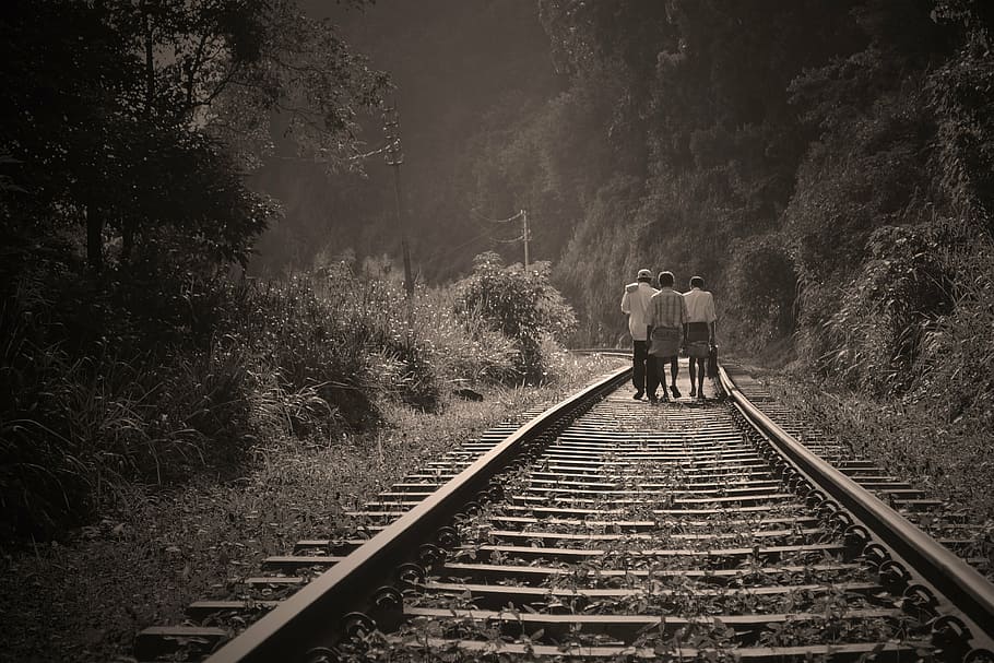 grayscale photo of three persons walking on railway, rail road