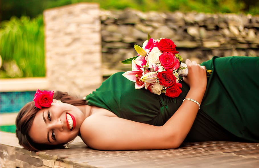 woman in green dress laying down on brown wooden surface during daytime