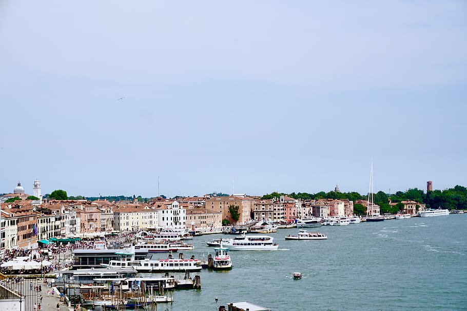 aerial photography of boats dock in front of buildings at daytime, aerial photography of building and boat during daytime HD wallpaper
