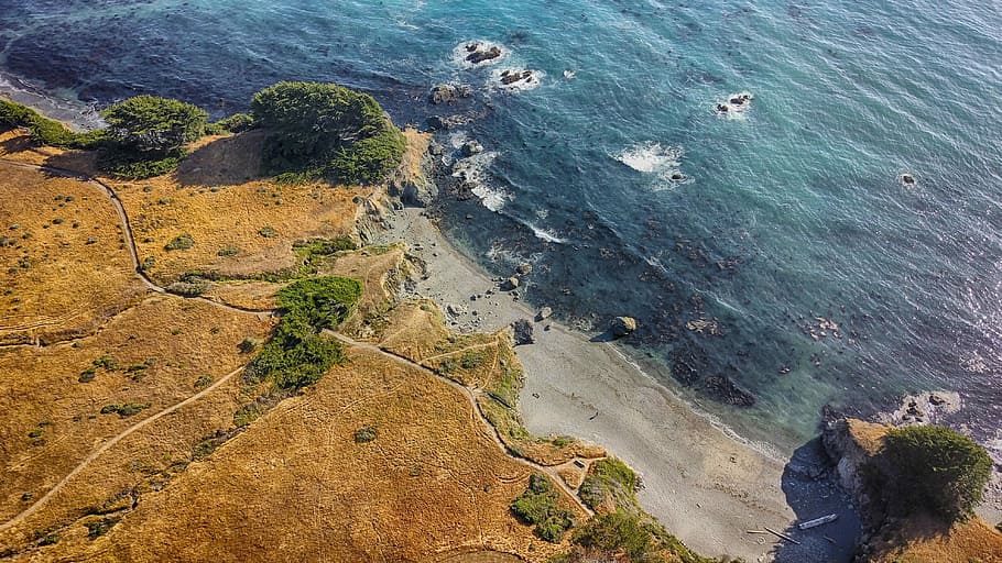 high-angle photography of brown mountain beside body of water at daytime, aerial view of seashore HD wallpaper