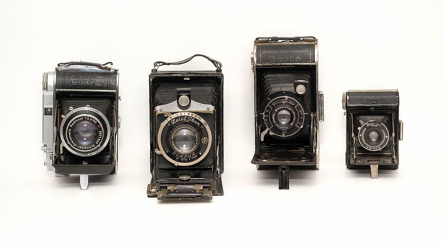four black folding cameras on white surface, vintage, german