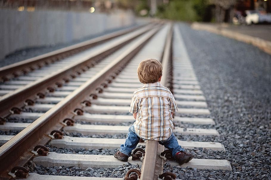 depth of field photography of boy sitting on brown metal train railway HD wallpaper