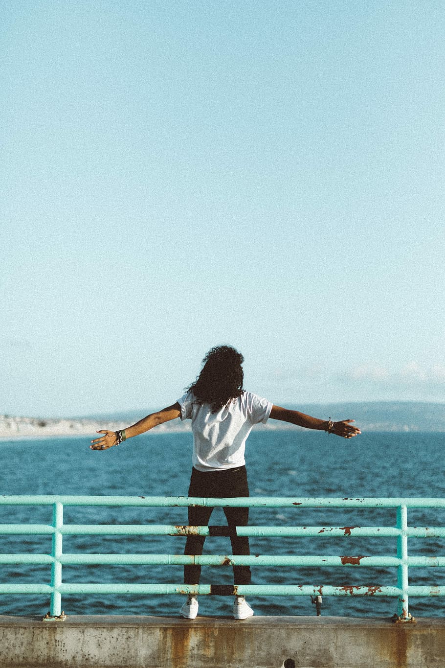 woman standing in front of sea under clear blue sky, woman standing beside metal rails in front of water during daytime HD wallpaper
