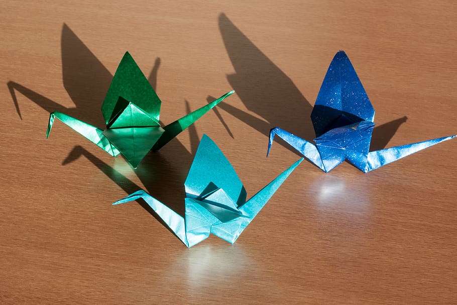 three blue and green origami on brown wooden table, art of paper folding