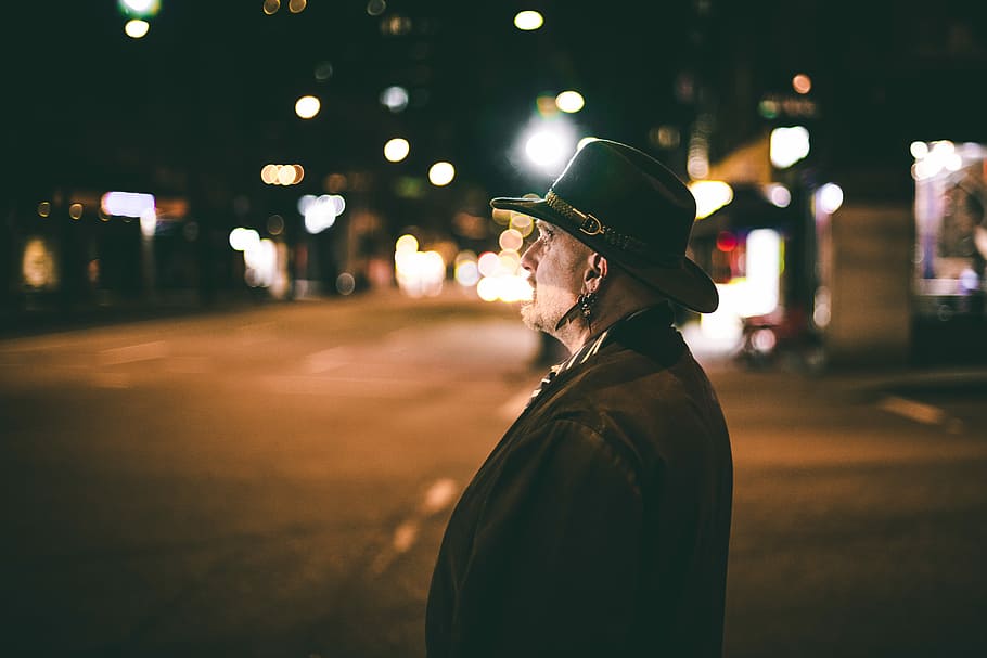 man standing on roadside at night time, man staring out of nowhere wearing black hat HD wallpaper