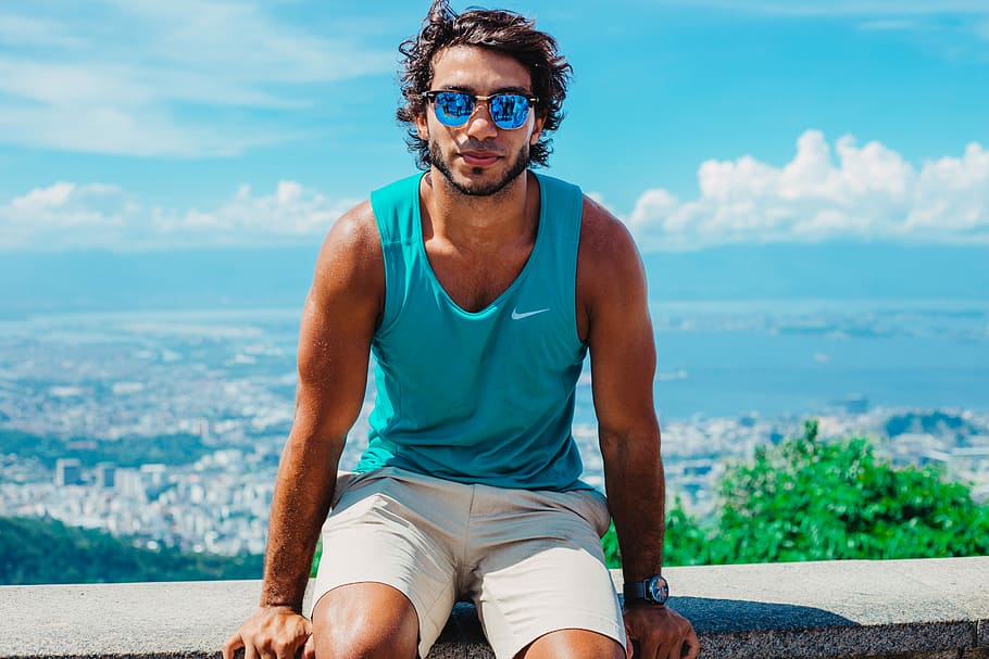 man sitting on grey concrete bench with overview of city on background during daytime, man sitting on gray concrete surface during daytime HD wallpaper