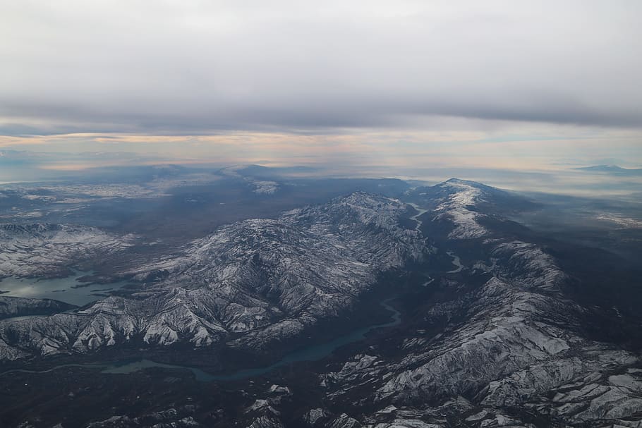 aerial photography of gray mountains, aerial photography of river between mountains under cloudy sky HD wallpaper