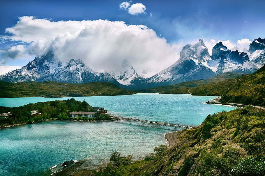 lake near snow-covered mountain during daytime, gray bridge thru other mountain HD wallpaper