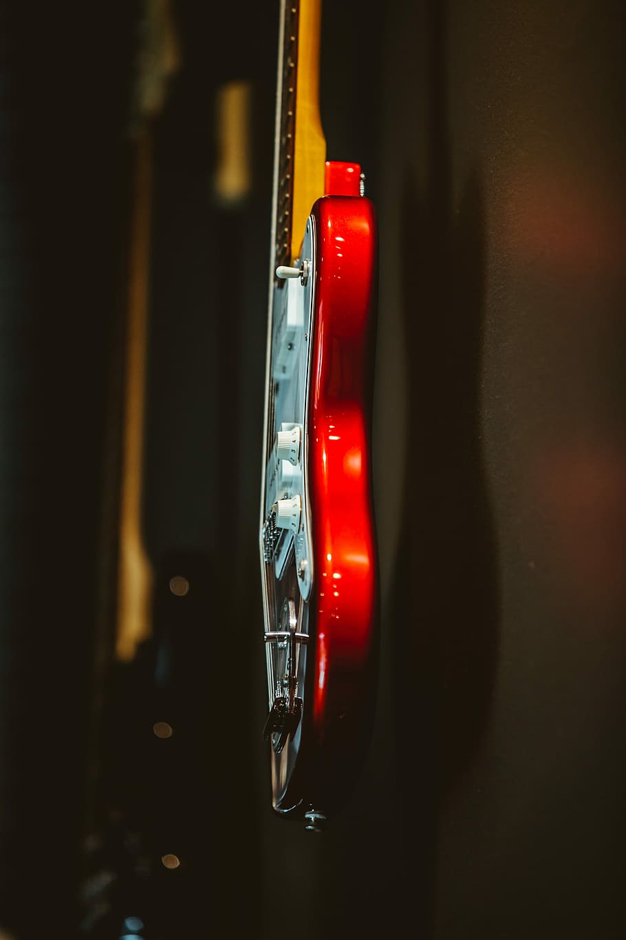 white and red stratocaster electric guitar hanging on wall, shallow focus photography of red and white electric guitar