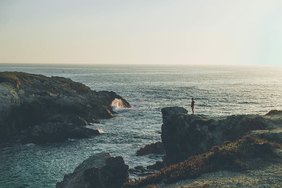 person standing on cliff near body of water, man standing on a cliff HD wallpaper
