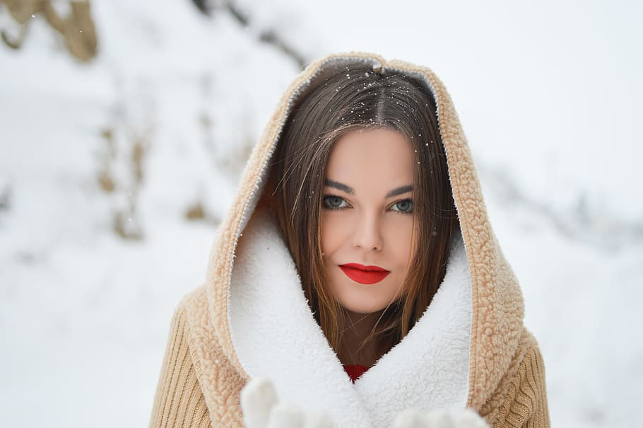smiling woman with winter coat during daytime, woman wearing brown and white coat with snow particles on her head focus photography