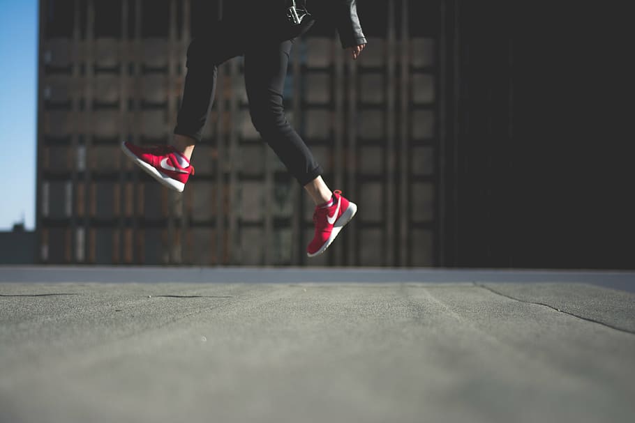 person wearing red Nike sneakers jumping on road during day, black, HD wallpaper