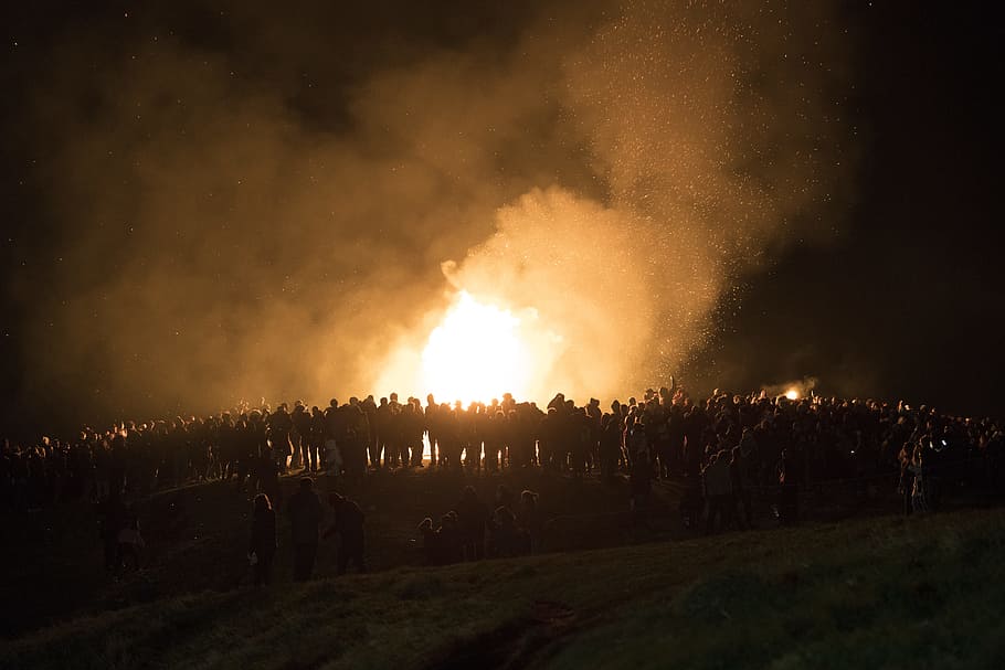 people gathered near bonfire during nighttime, people standing near fire during night time