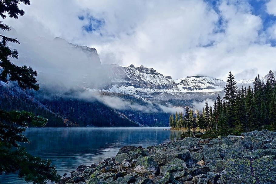 calm body of water near mountains and trees under blue sky and white clouds during daytime HD wallpaper