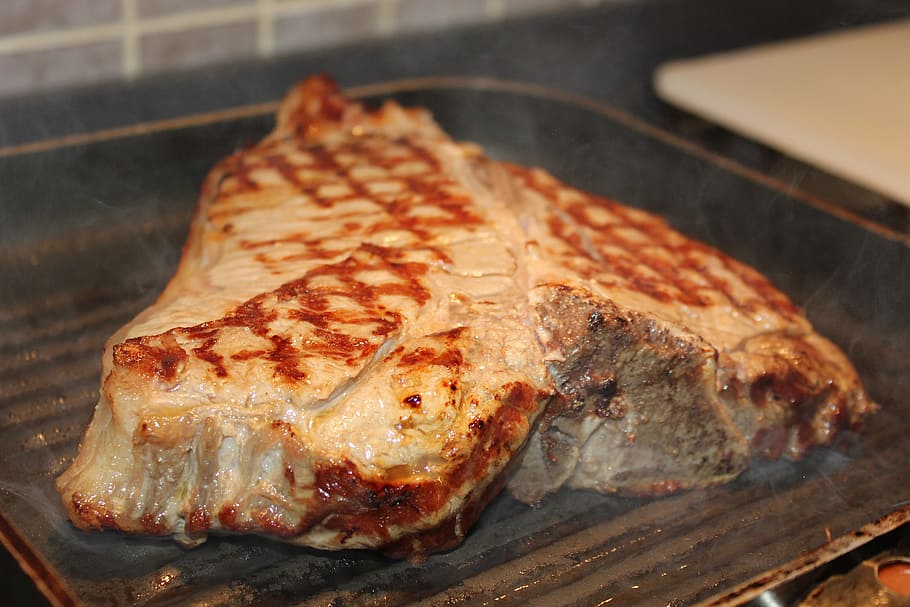 grilled meat on top of black metal grilling pan, fiorentina, tuscany