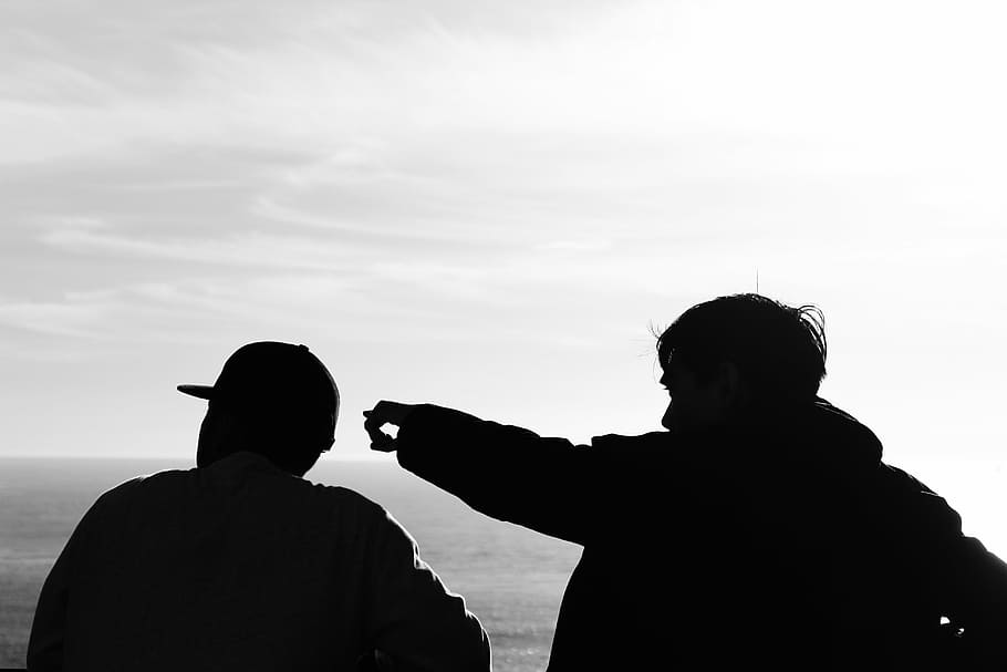 silhouette photography of two men facing body of water, close