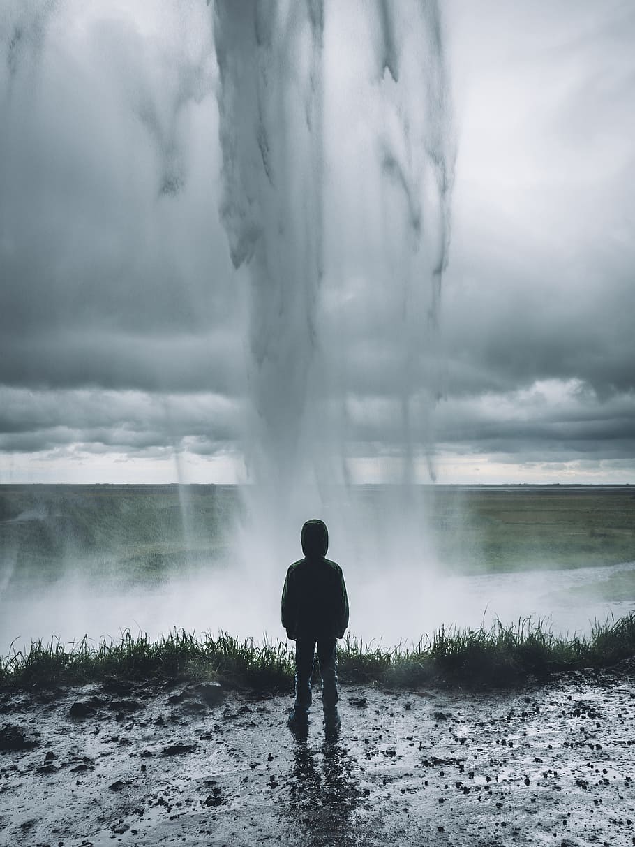 person standing facing on geyser photograph, waterfalls, grass