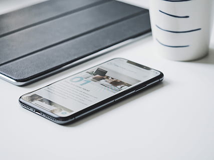 black smartphone beside black smart case, black smartphone on white board beside cup HD wallpaper