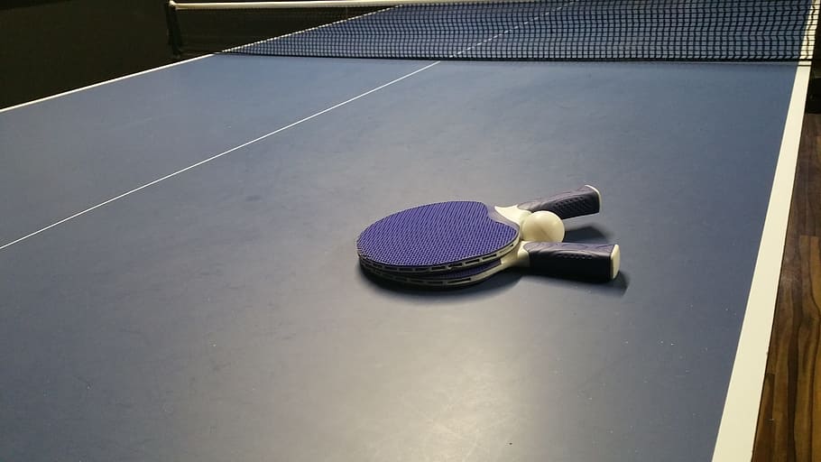 close-up photo of blue-and-white ping-pong paddle on top of ping-pong table
