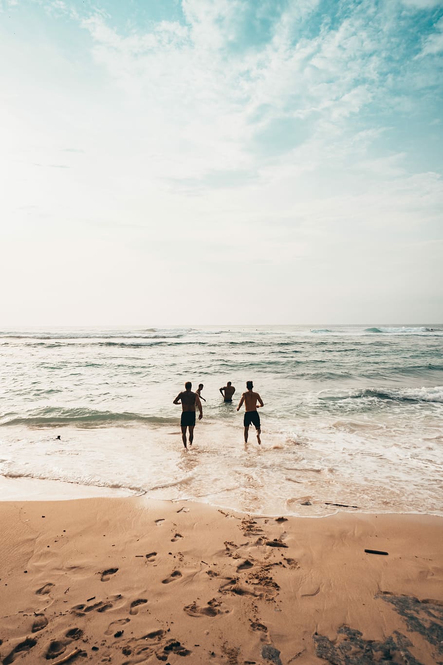 four person on beach during daytime, sand, sea, water, seashore