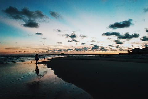 silhouette of person walk through beside ocean under blue and cloudy sky during sunset, silhouette of person standing on seashore at dusk HD wallpaper