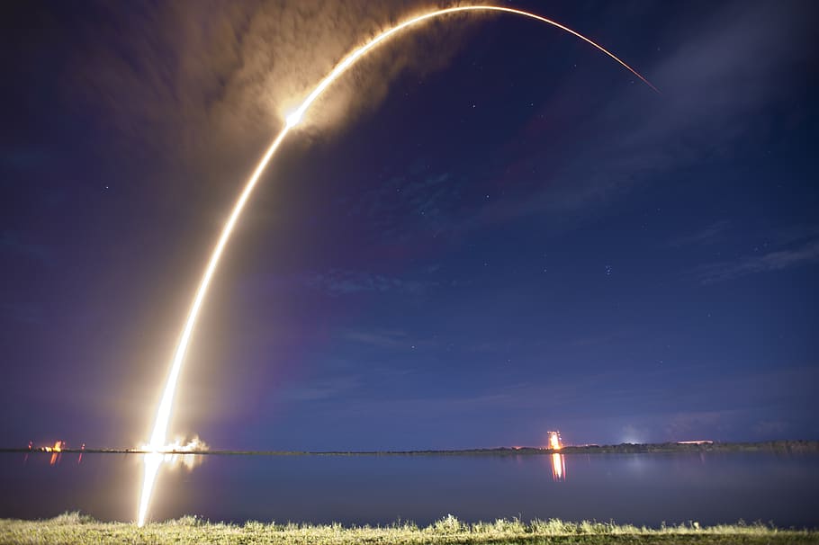 yellow light toward body of water during nighttime, rocket launch