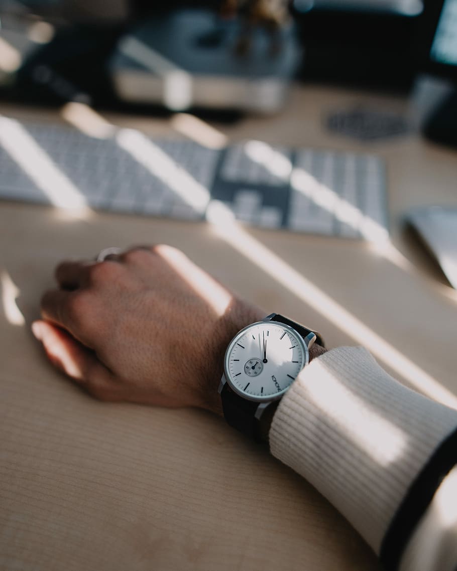 shallow focus photography of men's round white analog watch, person's hand on top of brown table HD wallpaper