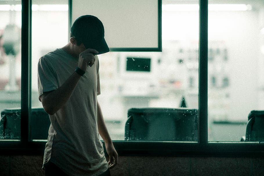 man in gray crew-neck t-shirt holding his cap, man holding cap while looking down HD wallpaper