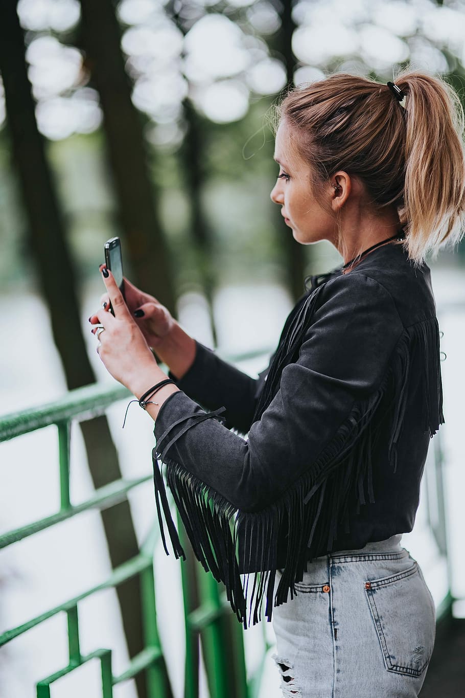 Blonde woman in a black jacket and ripped jeans by a green handrail, HD wallpaper