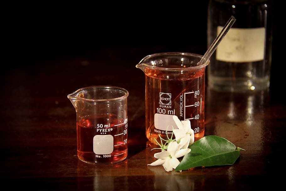 two 50 and 100 ml glass flasks with pouring lips filled with liquids on table