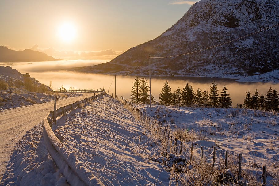 road near misty body of water, snow covered road overlooking sunset HD wallpaper