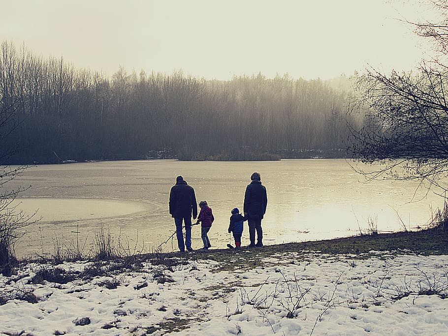 4-member family standing beside body of water during daytime