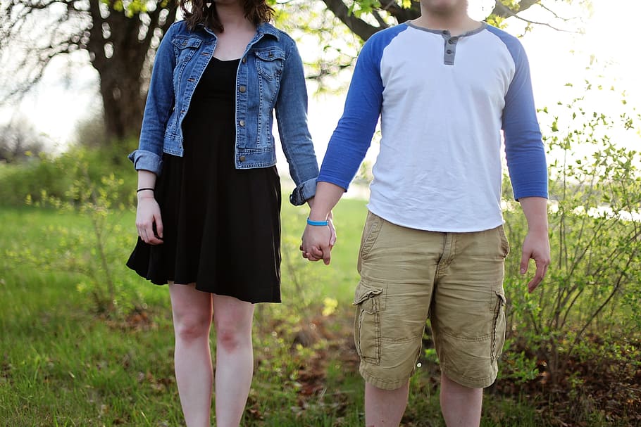 man and woman holding hands while standing on green grass field HD wallpaper