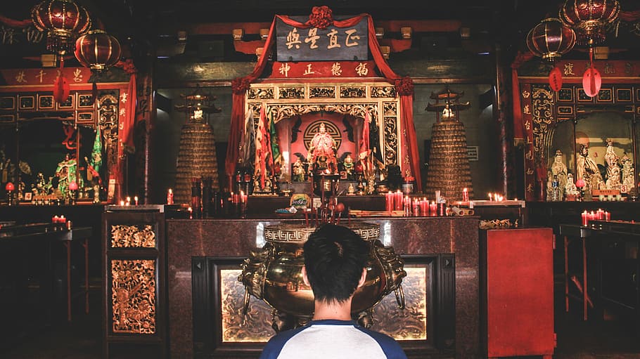 person wearing blue and white top watching statuettes in the room, man standing in front of altar HD wallpaper