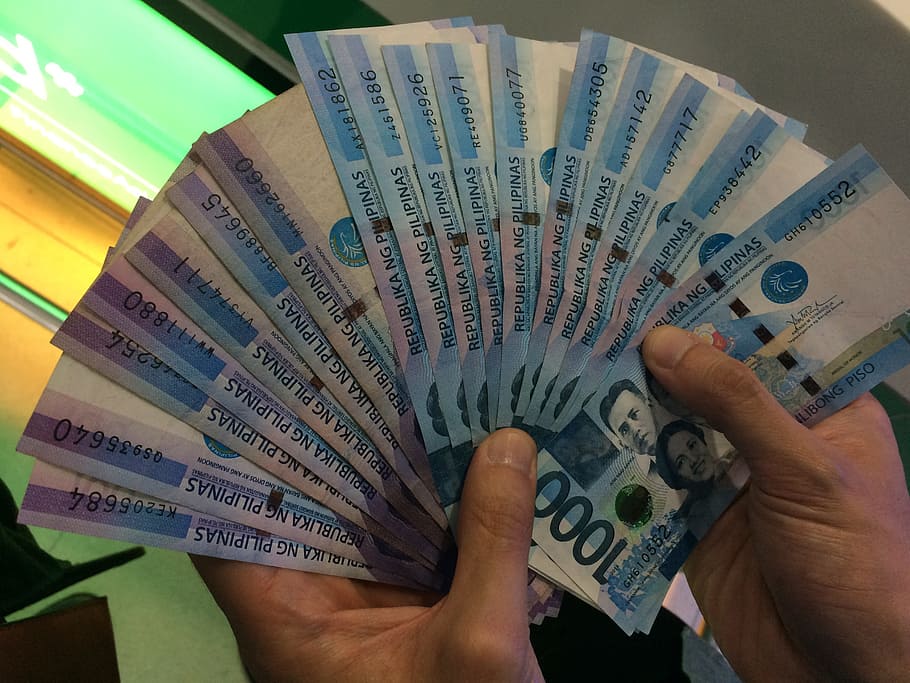 person holding bundle of 1000 Philippine peso banknotes, Silver