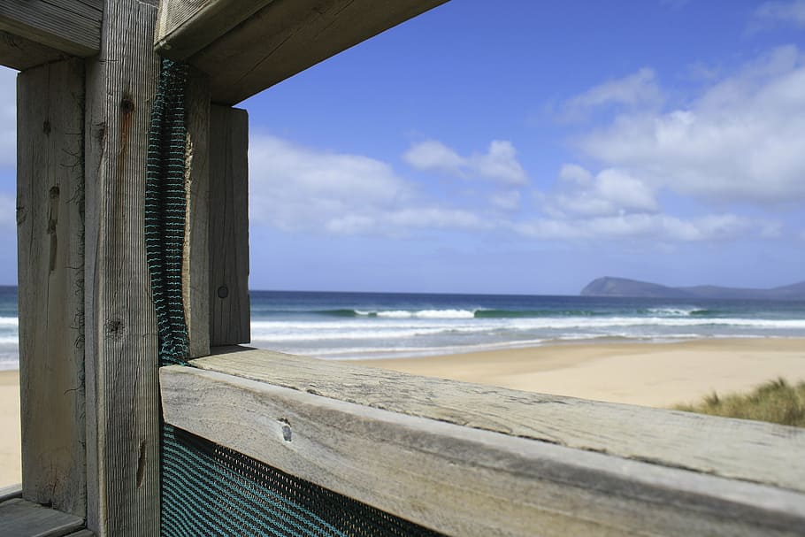 close-up photo of grey wooden stand beside seashore at daytime HD wallpaper