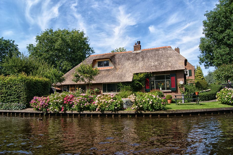 photo of house near body of water, brown house, flowers, giethoorn